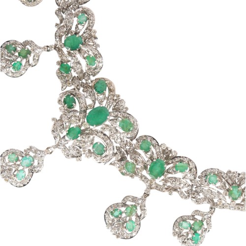 70 - An Emerald and Diamond Necklace,

the graduated floral scrollwork collar claw-set with oval mixed-cu... 