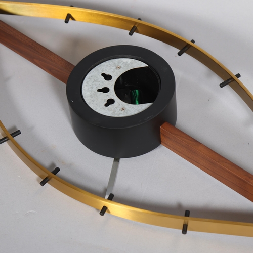 143 - A mid-century design wall clock in the form of an eye, the brushed brass frame curving around a waln... 