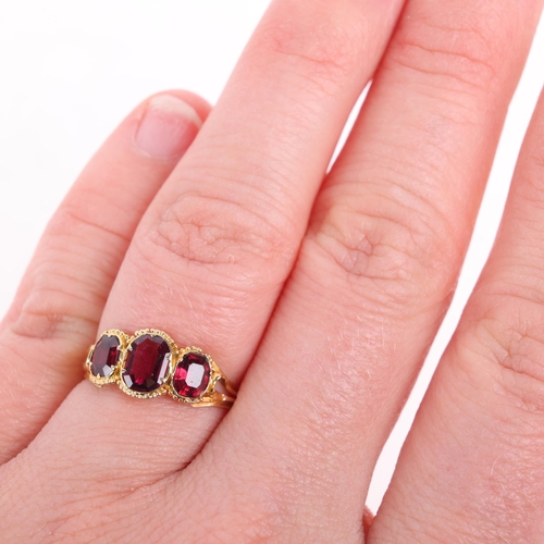 1121 - An Antique Georgian three-stone garnet ring, collet set with octagonal step-cut garnets, within bead... 