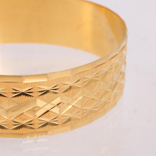 1131 - A Middle Eastern 21ct gold slave bangle, textured and etched lozenge decoration, band width 18.5mm, ... 