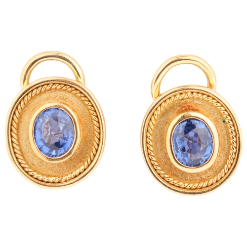 1144 - A pair of 18ct gold sapphire earrings, each rub-over set with a 0.65ct oval mixed-cut sapphire withi... 