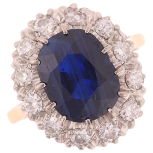 1145 - An 18ct gold sapphire and diamond cluster ring, claw set with 3.7ct oval mixed-cut sapphire surround... 