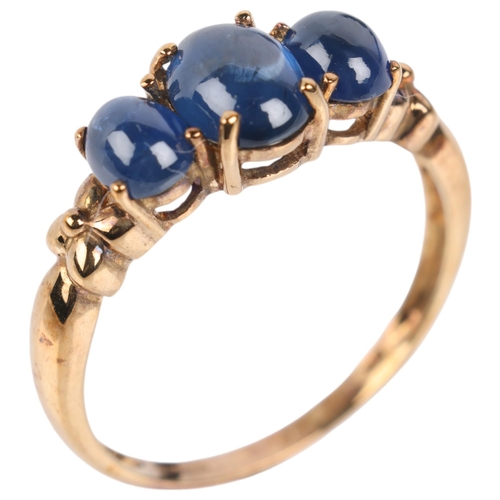 1255 - A 9ct gold three stone sapphire ring, claw set with oval cabochon sapphires, setting height 6.8mm, s... 