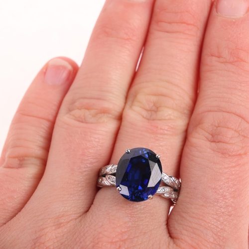 1275 - An 18ct white gold synthetic sapphire and diamond dress ring, claw set with oval mixed-cut sapphire ... 