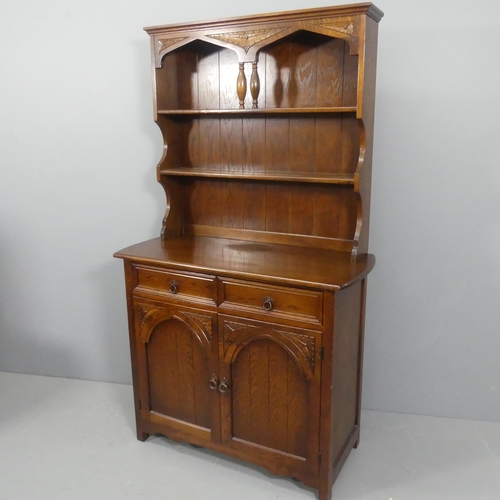 2125 - A reproduction oak two-section dresser, with open plate rack, two drawers and arch panelled cupboard... 