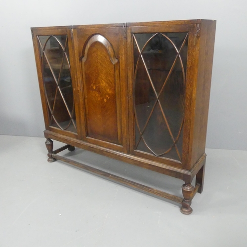 2126 - A 1930s oak bookcase, with one arch panelled and two lattice glazed doors. Width 134cm, height 113cm... 