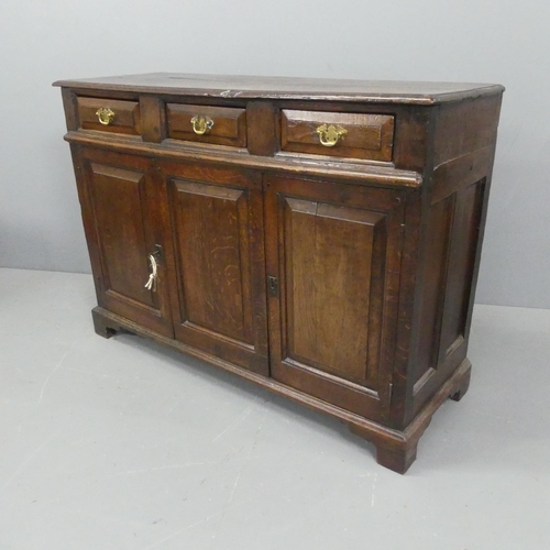 2183 - A Georgian oak sideboard, with three drawers above three fielded panelled doors and raised on bracke... 