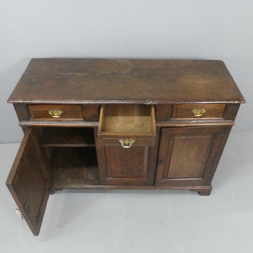 2183 - A Georgian oak sideboard, with three drawers above three fielded panelled doors and raised on bracke... 