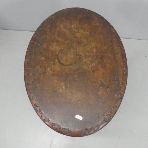 2186 - An oak and mahogany oval tilt-top occasional table, with carved decoration and raised on turned cent... 