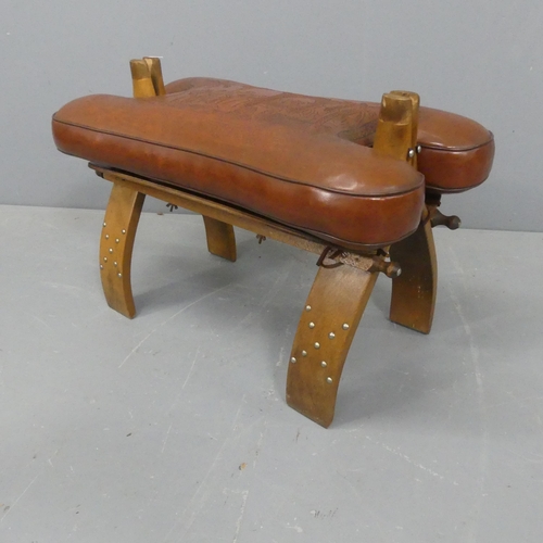 2214 - A camel saddle design footstool, with oak base and leather cushion. Width 63cm, height 42cm, depth 3... 