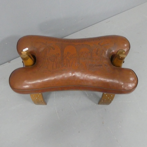 2214 - A camel saddle design footstool, with oak base and leather cushion. Width 63cm, height 42cm, depth 3... 