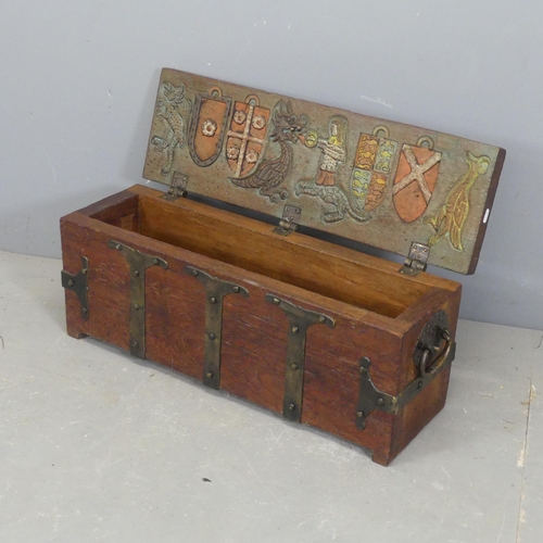 2588 - A metal bound teak trunk, the lid lifting to reveal armorial mythological carved and painted designs... 