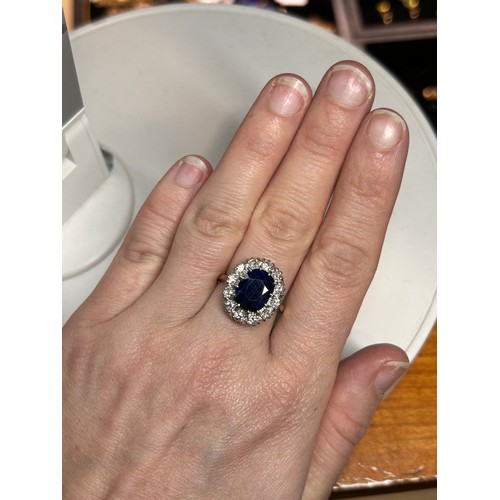 1145 - An 18ct gold sapphire and diamond cluster ring, claw set with 3.7ct oval mixed-cut sapphire surround... 