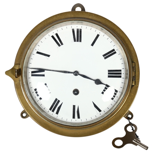 292 - A brass-cased ship's bulkhead clock, in working order, diameter 19cm, with key