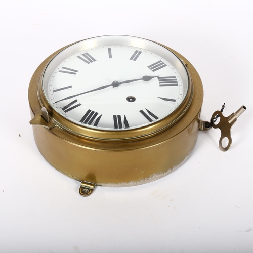 292 - A brass-cased ship's bulkhead clock, in working order, diameter 19cm, with key