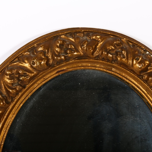 302 - An ornate composite oval wall mirror, 65cm x 56cm