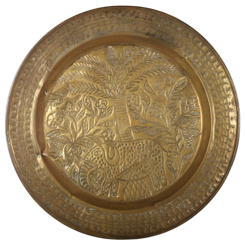 33 - A large Indian brass charger/wall plate, with allover boss decoration depicting an elephant and flow... 