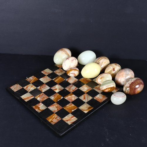 352 - A collection of carved hardstone eggs, and a similar chess board, 26.5cm