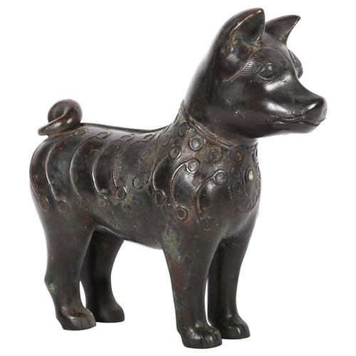 424 - An Oriental patinated bronze figure of a dog with a curly tail, with embossed decoration, H25.5cm