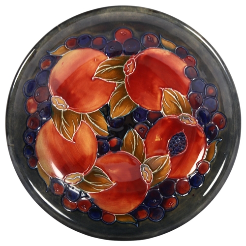 693 - A Moorcroft Pomegranate design dish, with dark blue and green ground background, signed and stamped ... 