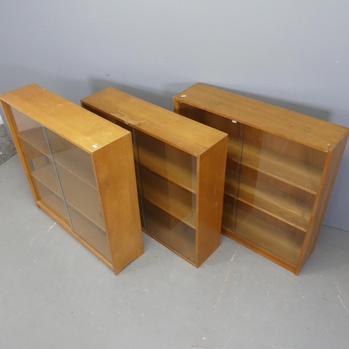 2551 - Three mid-century teak bookcases with glass sliding doors, all labelled for Phonix Gallery, London, ... 