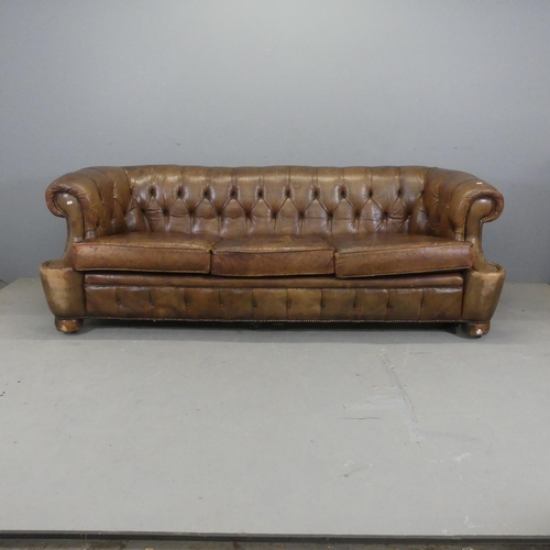 2552 - An antique brown button-back studded-leather upholstered Chesterfield sofa. Overall width 215cm, hei... 