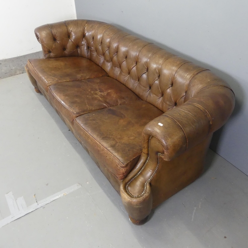 2552 - An antique brown button-back studded-leather upholstered Chesterfield sofa. Overall width 215cm, hei... 