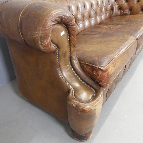 2552 - An antique brown button-back studded-leather upholstered Chesterfield sofa. Overall width 215cm, hei... 