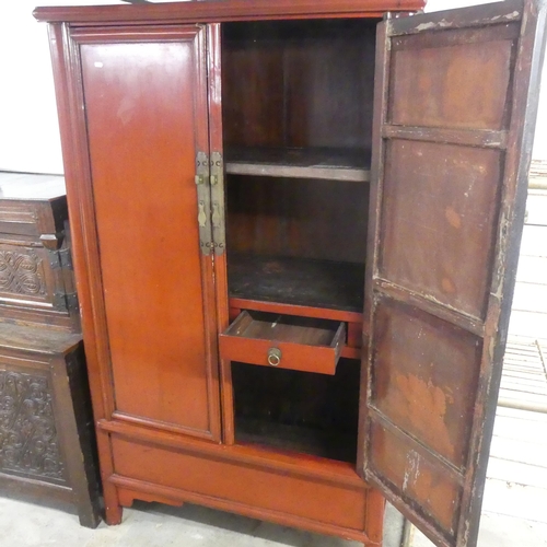 2589 - A Chinese red-lacquered two door cabinet. Width 108cm, height 185cm, depth 52cm.