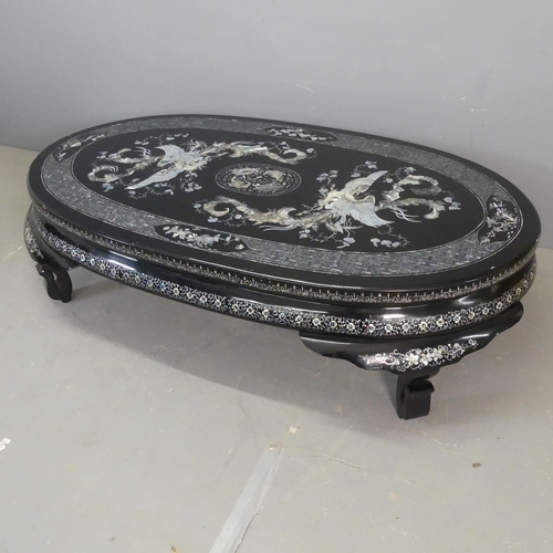 2693 - A modern Korean black lacquered oval low coffee table, with inlaid mother-of pearl phoenix decoratio... 