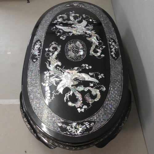 2693 - A modern Korean black lacquered oval low coffee table, with inlaid mother-of pearl phoenix decoratio... 