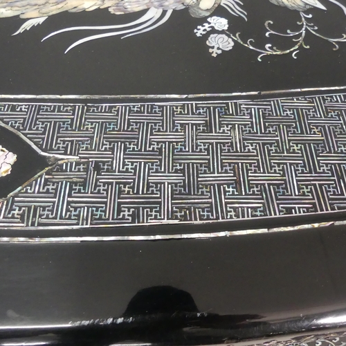 2693 - A modern Korean black lacquered oval low coffee table, with inlaid mother-of pearl phoenix decoratio... 