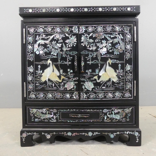 2697 - A Korean black lacquered jewellery cabinet, with two doors revealing a drawer fitted interior, a sin... 