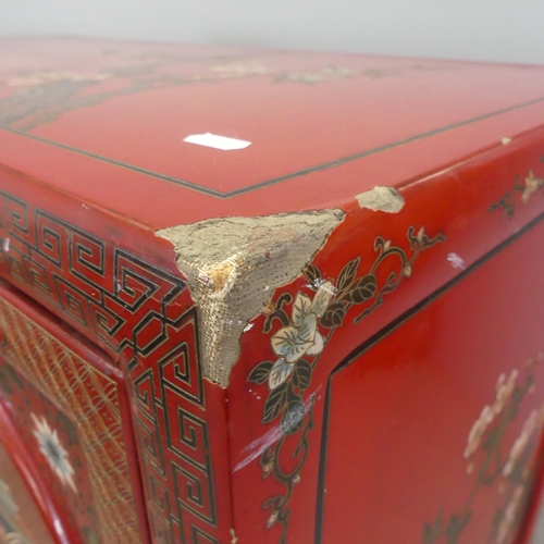 2706 - An early 20th century Chinese red-lacquered cabinet, with hand painted decoration, two doors reveali... 