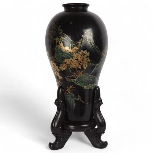 89 - A large Chinese black lacquered wood vase on stand, with gilt mountain landscape decoration, overall... 