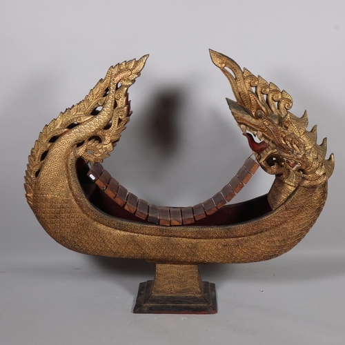 50 - A large Thai floor standing dragon boat design xylophone, carved and gilded wood, 20th century, leng... 