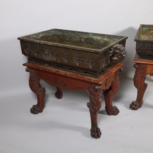 51 - A near pair of massive Chinese patinated bronze planters on oak stands, with elephant and dragon han... 