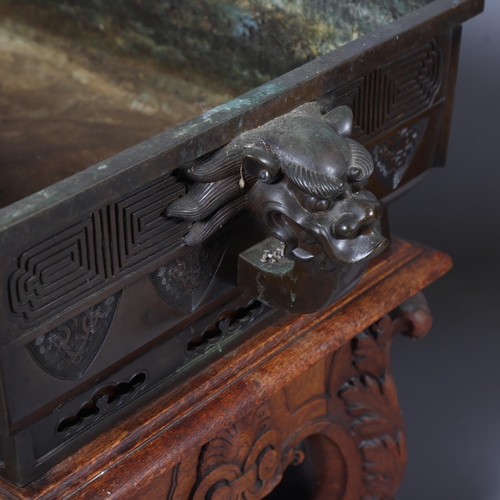 51 - A near pair of massive Chinese patinated bronze planters on oak stands, with elephant and dragon han... 