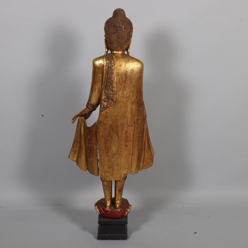 58 - A Burmese 20th century carved giltwood standing Buddha, on lotus base, height 100cm