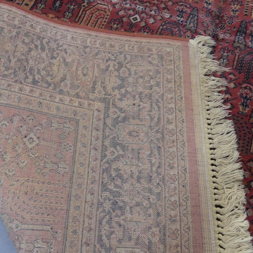 2300 - A red-ground Persian machine made rug. Length 242cm, width 160cm.