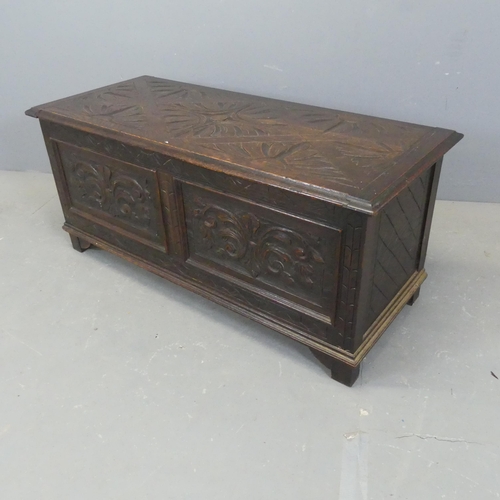 2345 - A panelled oak coffer with carved decoration. Width 106cm, height 46cm, depth 46cm.