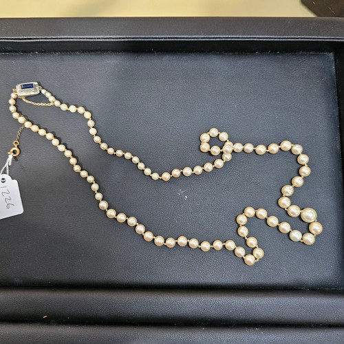 1226 - A single-strand pearl bead necklace, set with 8.1-3.3mm pearls, with 9ct gold synthetic? sapphire an... 