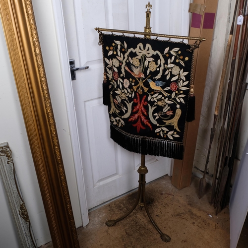 138 - An Antique engraved brass pole stand, on tripod legs and leaf feet, with an embroidered hanging tape... 