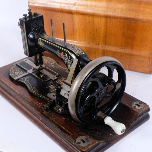 203 - An early 20th century Fiddle base hand-crank sewing machine, painted decoration with walnut case