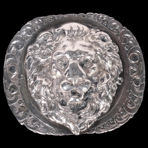 611 - An unmarked white metal brooch, lion mask central panel flanked by a scrolled border, diameter 42mm