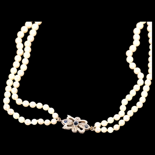 636 - An Art Deco style double-strand pearl necklace, set with a 9ct white gold clasp set with sapphires, ... 