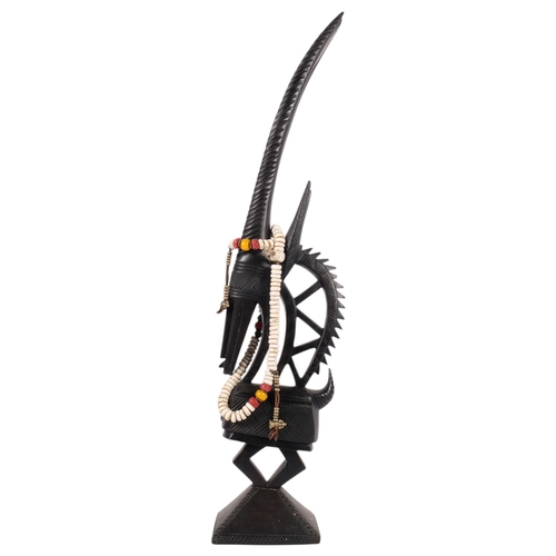 682 - An African stylised carved hardwood sculpture of an antelope, 73cm, and a bead necklace