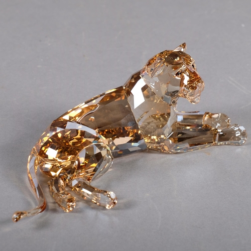 944 - SWAROVSKI - a tinted model of a recumbent lioness, 18cm, boxed