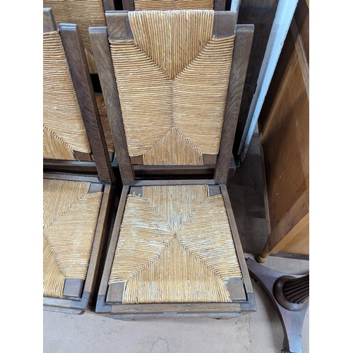 2071 - CHARLES DUDOUYT - A set of four mid-century brutalist oak dining chairs, each with rush drop-in seat... 