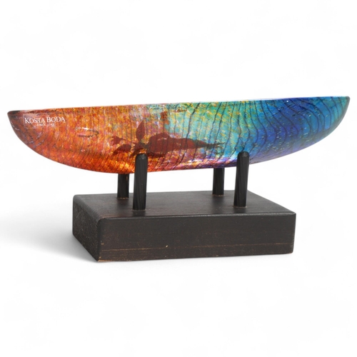 241 - BERTIL VALLIEN for Kosta Boda, a cast glass boat sculpture on a black wooden cradle. The boat is in ... 